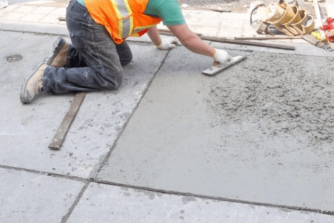 Contractor hand-troweling a concrete repair section on a public sidewalk