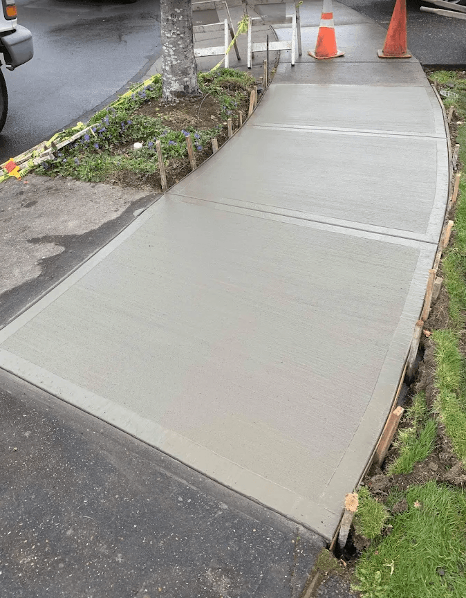 Newly poured concrete public sidewalk curving along a residential street